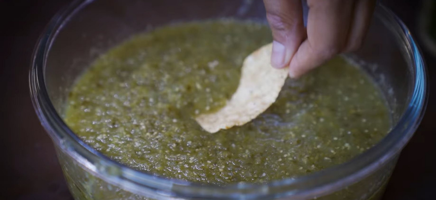 Chip being dipped into salsa verde
