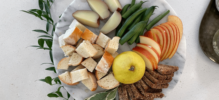 Cut up apples, bread, green beans and a pear on a plate