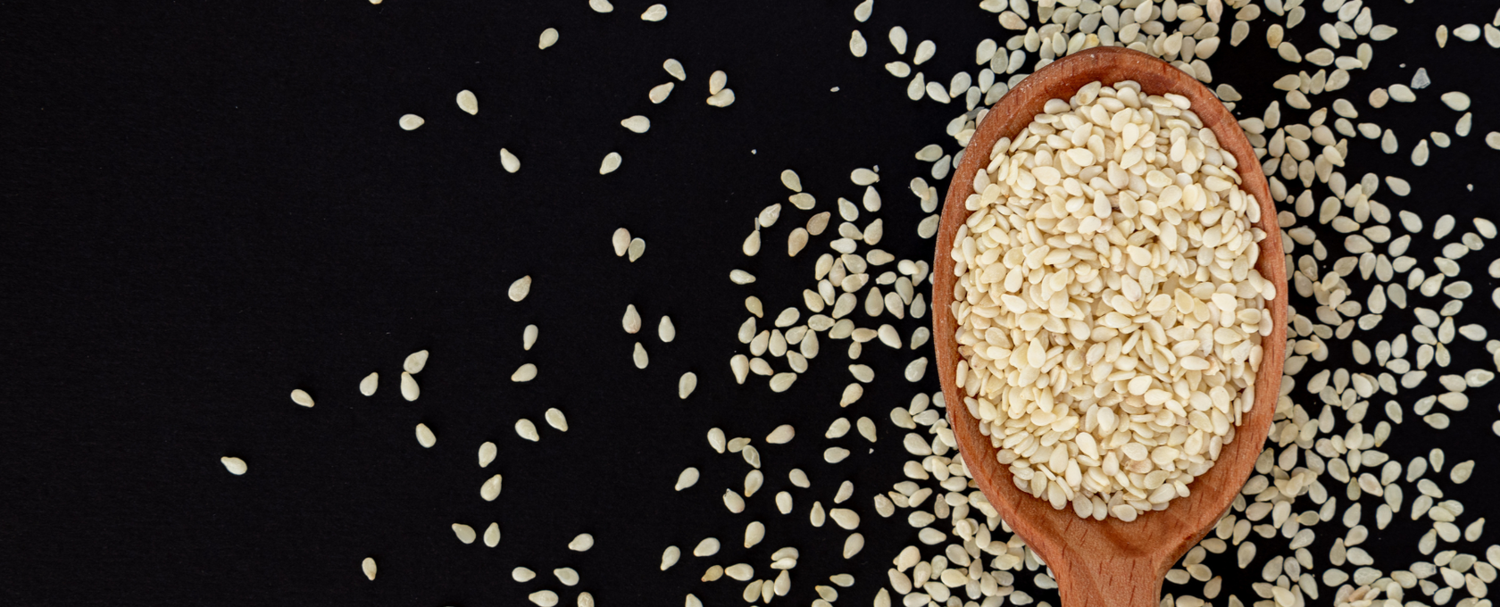 Sesame seeds in a spoon and on a table