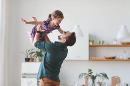 Dad holding daughter above his head