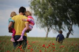 father and children walking toward tree