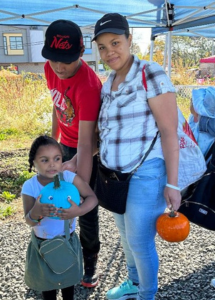 A picture of a family with a little girl holding a teal pumpkin