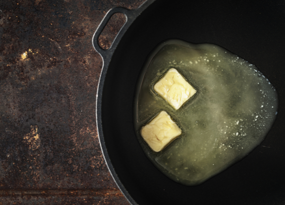 two slices of butter melting in a cast iron pan