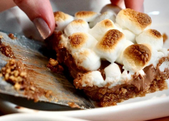 hand scooping a smores bar onto a dish