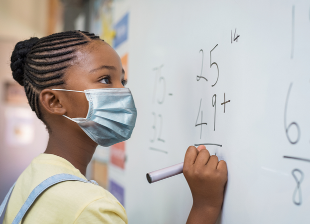 Girl doing a math problem on a whiteboard