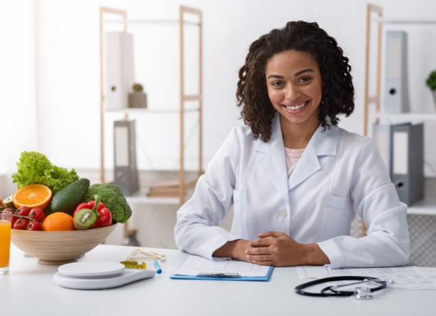 woman in white coat sitting by veggies