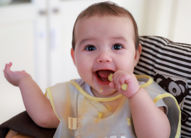 Happy baby eating baby corn