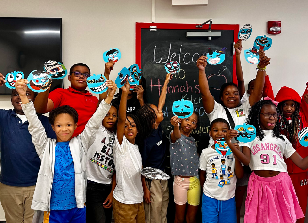 Kids in a classroom, holding teal pumpkins