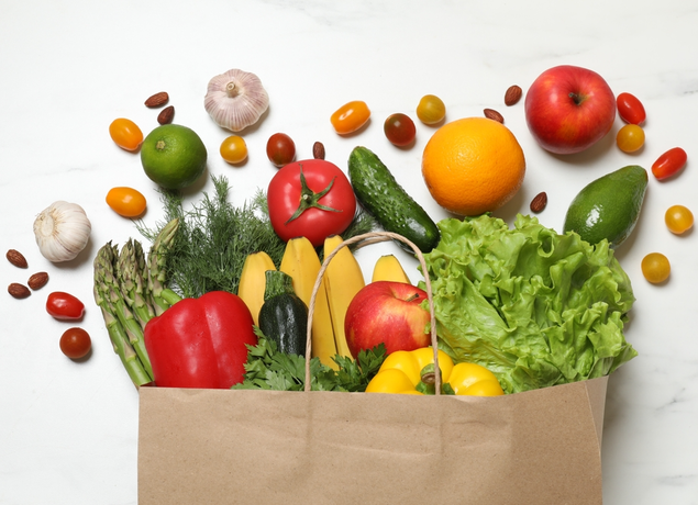 Paper grocery bag with fruits n dvegetables spilling out of the top